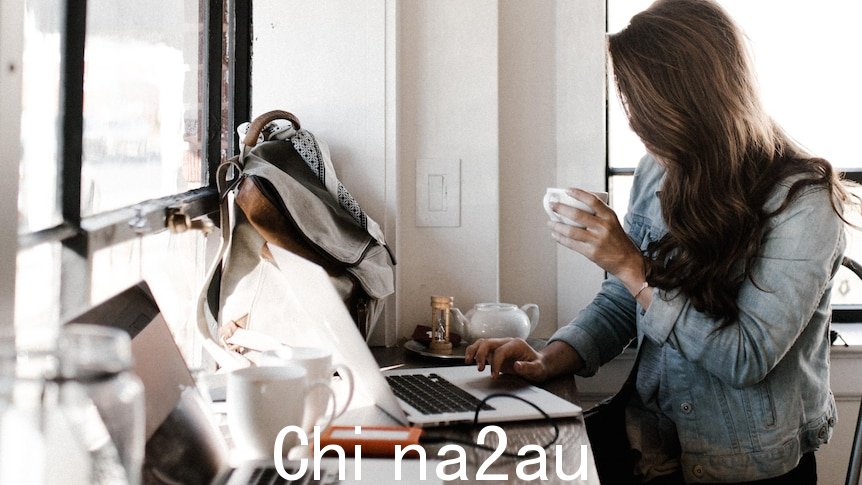 一位女士坐在电脑前喝咖啡，头发遮住脸。