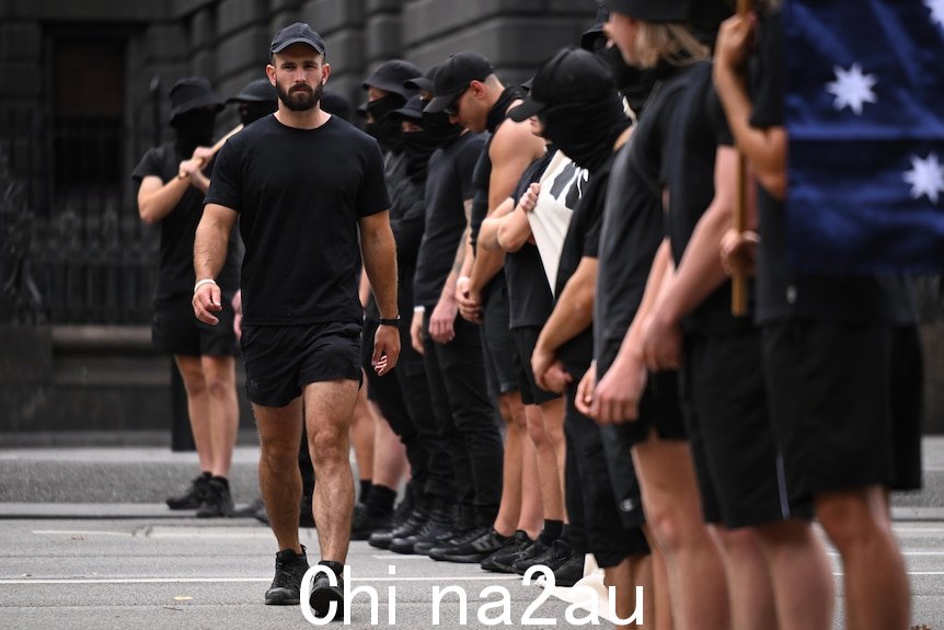 一个身穿黑色衣服的男人沿着一排同样穿着黑色衣服的男人走着。