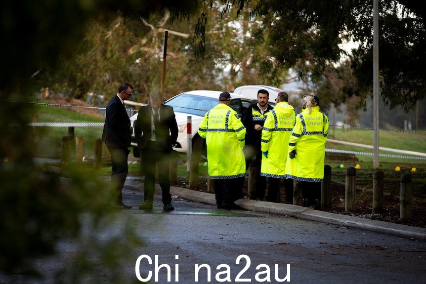 一组反光衣一名身穿西装的警察站在一辆白色汽车前。” /></p><p style=