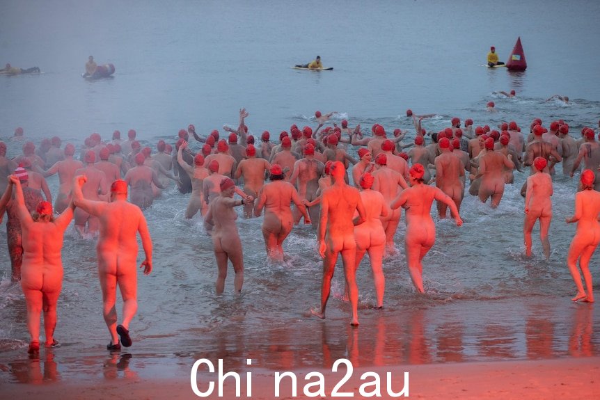 裸体游泳者集体冲入水中。