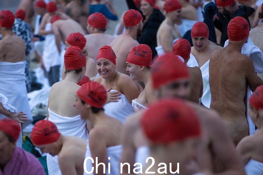 裸体游泳参与者在浸水后的兴奋戴着红色帽子。” width=