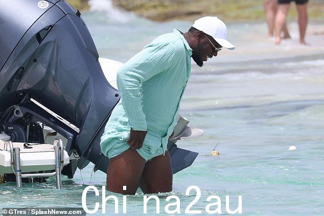 天哪!这位牙买加跑步者穿着蓝色外套看起来很酷,同时他试图不弄湿自己的衣服,同时从他的船上驶向海滩