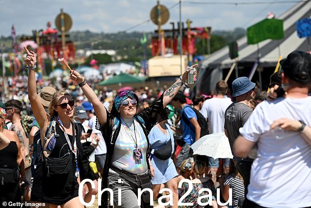 2023 年格拉斯顿伯里音乐节第二天到达公园区的节日观众,其中一位狂欢者在空中挥舞着双手