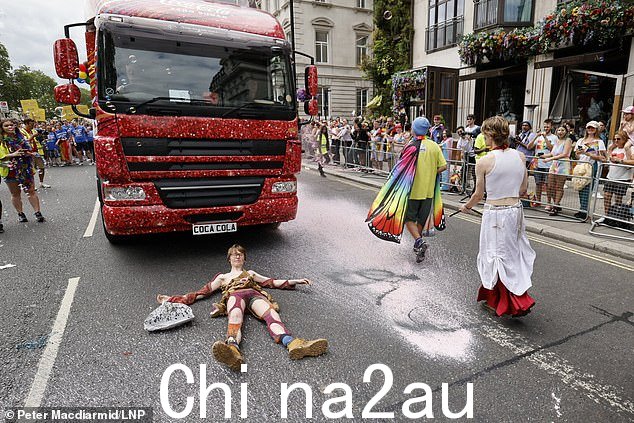当一名生态狂热者躺在路上时,其他人在停机坪上的可口可乐花车上喷洒黑色和粉色油漆