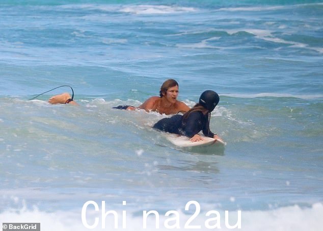 学习驾驭海浪:明星在尝试冲浪时戴着头盔
