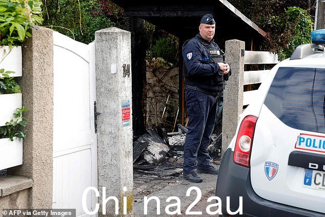周日,骚乱者将一辆汽车撞入巴黎郊区海莱罗斯,一名市政警察站在海莱罗斯市市长文森特·让布伦受损的住宅前。市长的妻子和他的一个孩子受伤的建筑物
