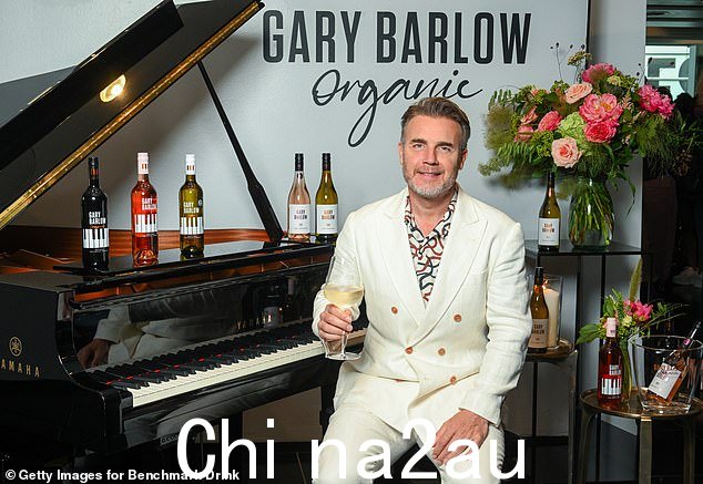 Dapper:Gary 坐在一架大钢琴前,钢琴上摆满了他的新葡萄酒,他在号码下面摇晃着一件彩色图案的开领衬衫