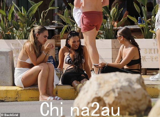 休息一下:一些女孩在等待进入餐厅时坐在路边,其他女孩则检查手机