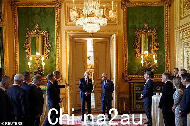 约翰·克里(左举手)在温莎城堡内的吊灯下与拜登和查尔斯国王交谈