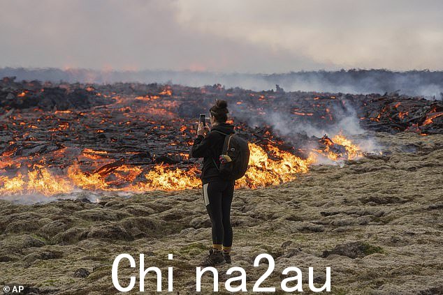 一个人在雷克雅未克西南约 30 公里(19 英里)处的 Fagradalsfjall 火山裂缝中行走的熔岩附近