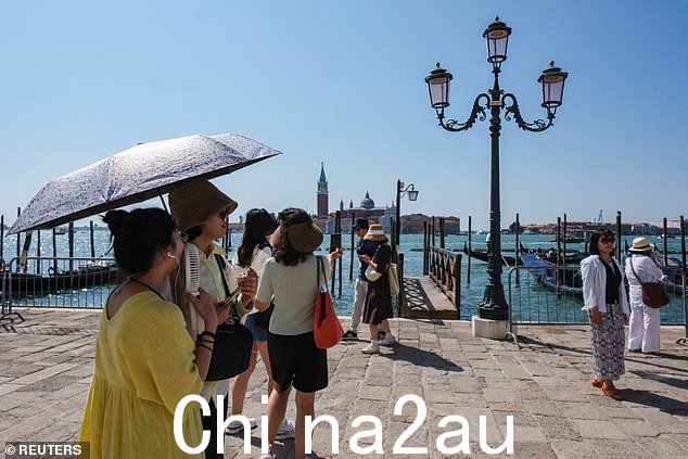 游客在圣马可广场打伞遮阳,这座城市正在为周六威尼斯的“救世主”节日庆祝活动做准备