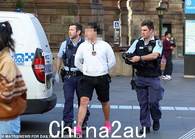一名男子被戴上手铐,并被一辆等待的警车带走