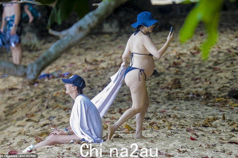 再见,伙计!当她走过一个朋友时,她戴了一顶 Prada 的深蓝色牛仔渔夫帽和窄框太阳镜