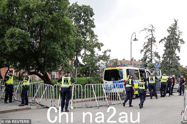 在瑞典斯德哥尔摩举行示威之前,警察站在伊拉克大使馆附近。一名抗议者准备焚烧《古兰经》