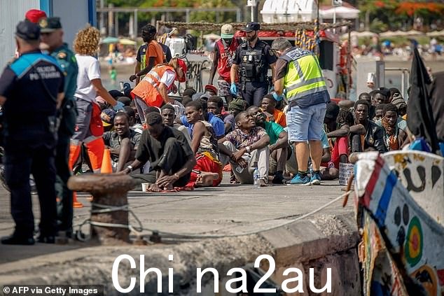 如图:移民从“cayuco”(木船)下船后在码头上休息。 2023 年 7 月 4 日在特内里费岛南部阿罗纳市洛斯克里斯蒂亚诺斯港开展的救援行动