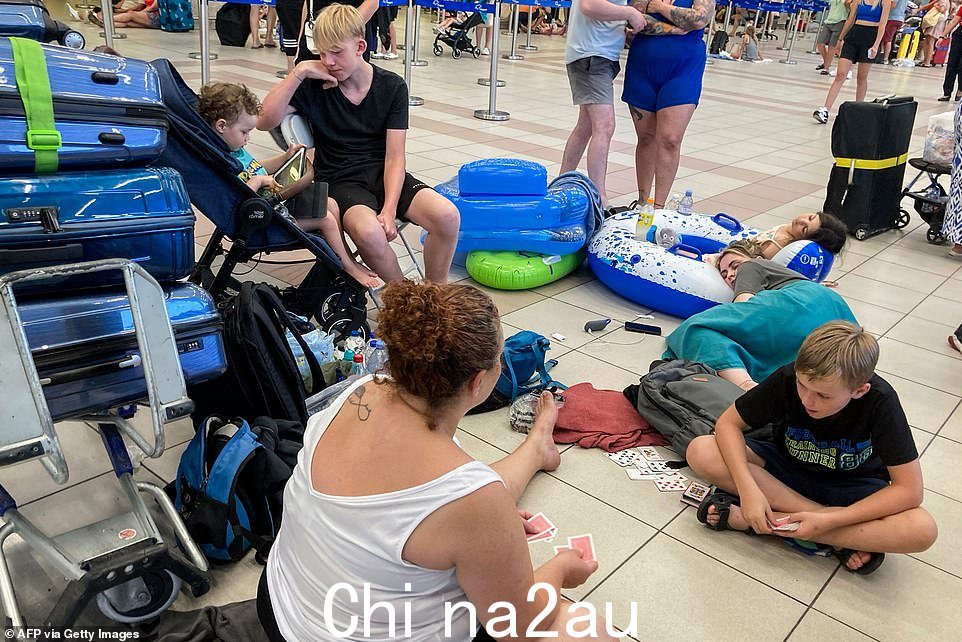希腊罗得岛,因山火引发疏散,游客在机场出发大厅等候时打牌