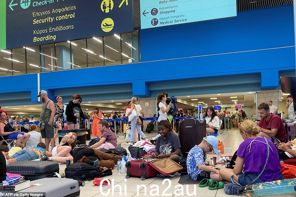 Tourists spread out across the floor as they wait in the airport's departure halls as evacuations are carried out from Rhodes