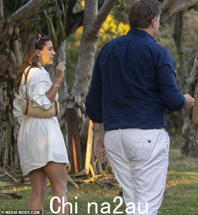 劳伦穿着奶油色衬衫裙,拎着稻草和皮革手提包