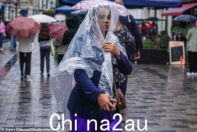 伦敦的一名行人在昨天的阵雨中躲在斗篷下