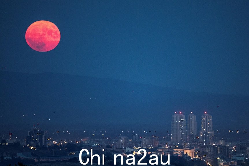 红色满月升起城市上空 