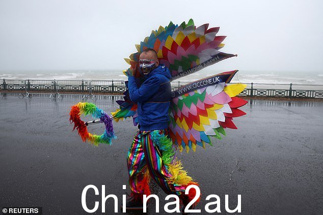 一个人的服装不是为天气而设计的 - 因为他正在努力阻止他的彩虹翅膀在风中飞行