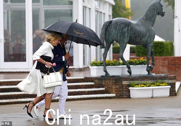 参加卡塔尔古德伍德节第五天的参赛者避雨