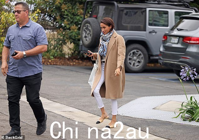 42 岁的苏塞克斯公爵夫人穿过一个停车场时,身边没有她的丈夫哈里王子,哈里王子目前在东南亚,她身边有一名保镖