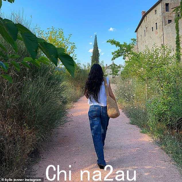 她穿着舒适的蓝色牛仔裤和飘逸的白色衬衫在该地区漫步