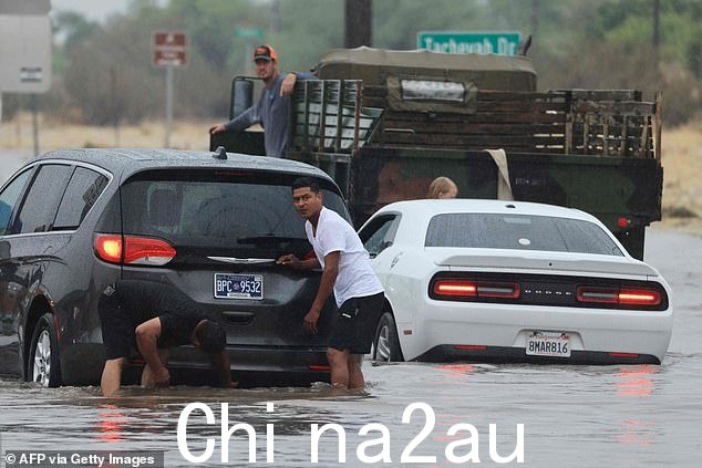在热带风暴希拉里带来的大雨期间,驾车者正在处理棕榈泉附近被淹没的道路和被困的车辆