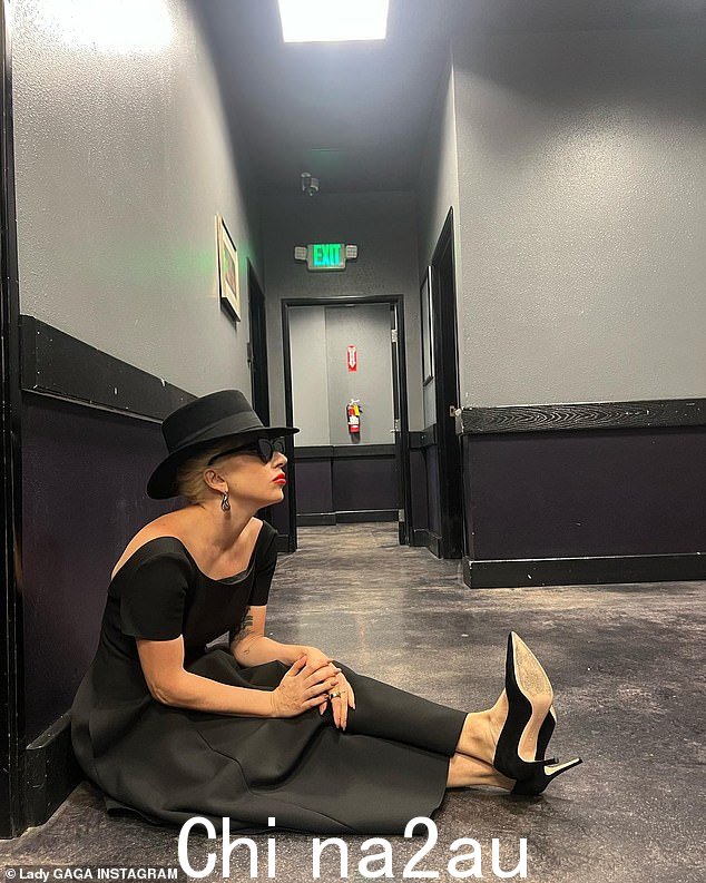 焦点:Lady Gaga 坐在地板上,双腿伸直,戴着黑色帽檐帽子,看上去陷入了沉思