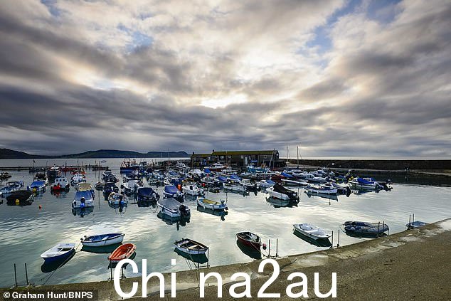 气象秋季第一天,多塞特郡莱姆里吉斯海滨度假胜地日出时,历史悠久的科布港上空的戏剧性天空