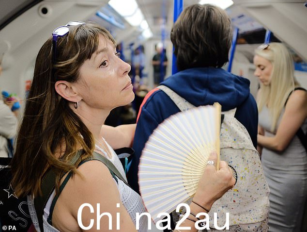 任何在夏季经常乘坐伦敦地铁的人都会感受到炎热和闷热的环境。图为：一名妇女在伦敦市中心的地铁列车上使用风扇降温