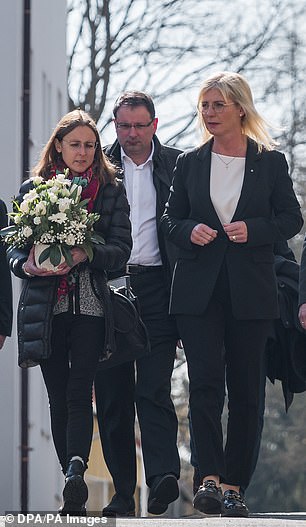 家庭事务部长乌尔里克·沙夫(Ulrike Scharf)(右)于四月离开儿童和青少年护理中心,在设施前献花