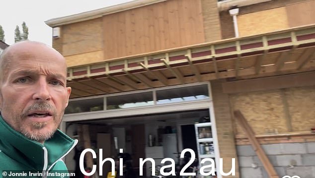 翻修:乔尼穿着绿色运动服夹克站在自家门前拍摄了一段自拍视频,展示了门廊的基本结构是如何建造的