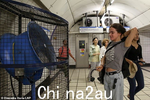 今天天气炎热,一位女士在伦敦地铁站的大风扇前纳凉