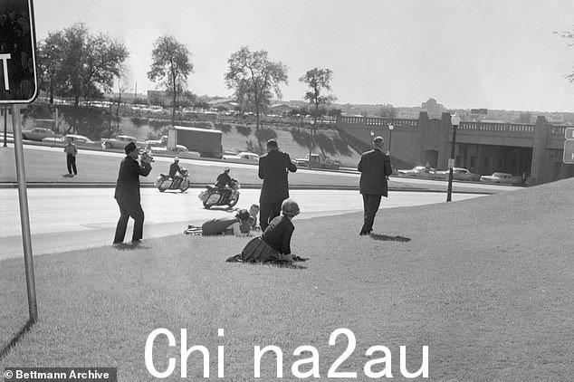 在狙击手子弹结束肯尼迪总统的生命后,旁观者躲在草丘上,车队护航加速离开