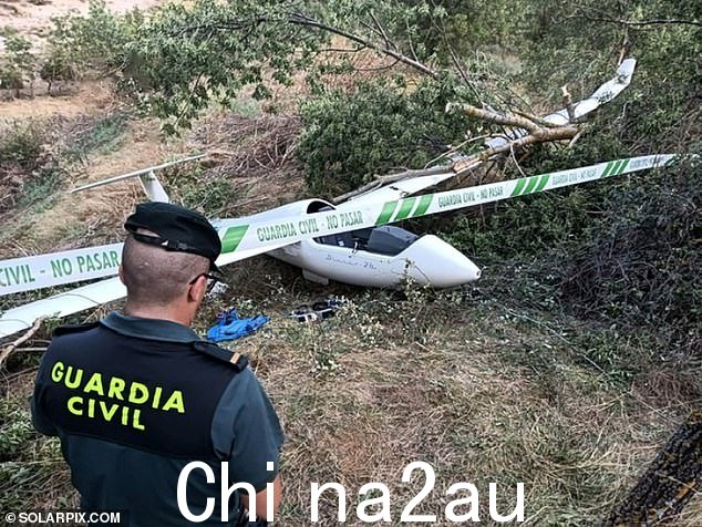Pictured is a Spanish policeman at the scene where the damaged glider is buried in undergrowth