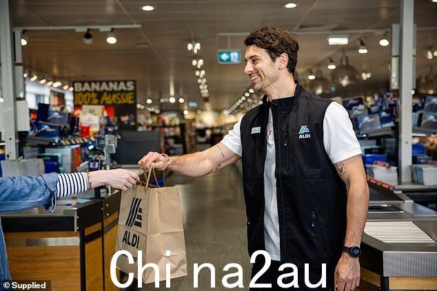 这位前学士明星穿着 ALDI 制服,忙着为顾客装杂货