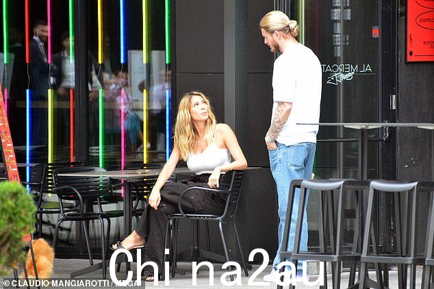 可爱:这对带着狗一起吃午餐的夫妇在露天餐厅外聊天