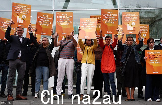 9 月 19 日,NHS 顾问在伦敦大学学院医院外的纠察队罢工时举着标语牌