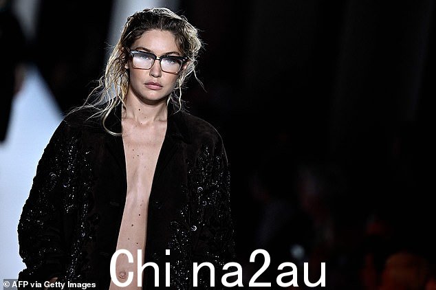 Glam:模特在展示设计师 2024 年春夏系列时,身穿开放式黑色亮片西装外套和配套裙子,不戴胸罩。
