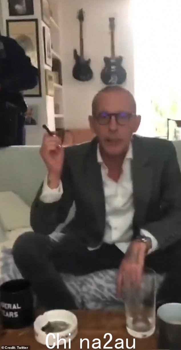 视频似乎显示,福克斯的客厅里有多名身穿制服的警官,福克斯坐在沙发上看着他们,身穿灰色西装,抽着雪茄