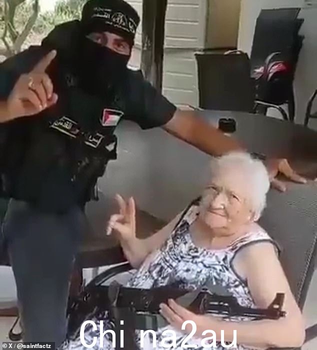 一名哈马斯战士与一名老年女性人质合影,这名女性人质在强迫她拿着步枪后可能已经丧失了智力