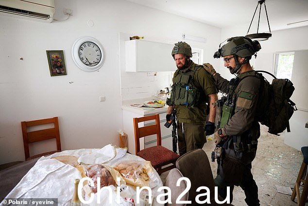 一名以色列士兵安慰他的部队成员,因为他们看着被哈马斯入侵的家中桌子上留下的未吃的面包