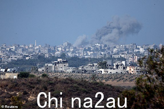 2023 年 10 月 15 日，从以色列南部以色列与加沙地带的边界看到的加沙地带天空中的烟雾和被毁坏的建筑物。路透社/Amir Cohen