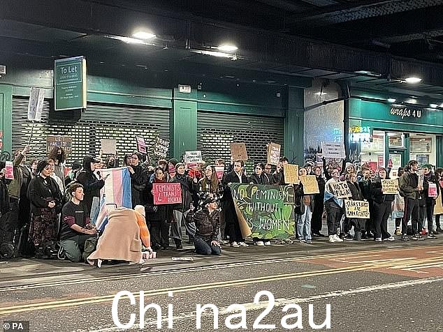 抗议者聚集在活动外,举着“没有跨性别女性就没有女权主义”的标语