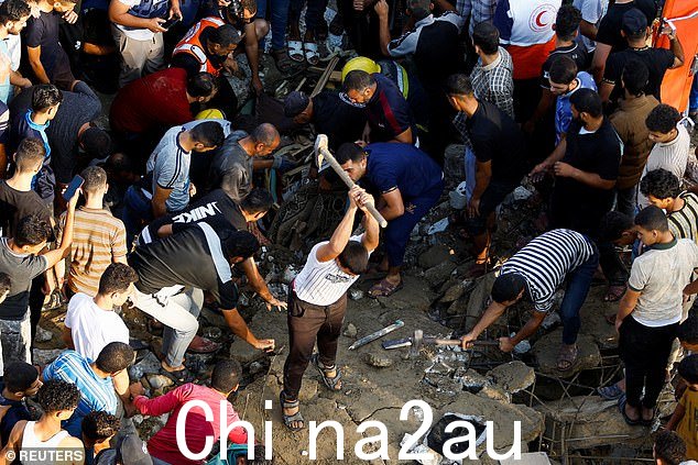 巴勒斯坦人在 2023 年 10 月 16 日加沙地带南部汗尤尼斯的以色列空袭中被摧毁的房屋废墟下搜寻伤亡人员
