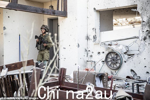 一名士兵检查废墟,其中包括破碎的家具和弹痕累累的墙壁