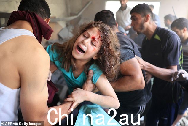  2023 年 10 月 17 日，以色列空袭加沙地带南部拉法难民营后，巴勒斯坦人从建筑物废墟中救出一名女孩