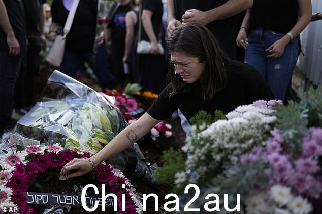 亚当女士在哈马斯袭击中被杀四天后,一名妇女在葬礼上在她的坟墓旁哭泣